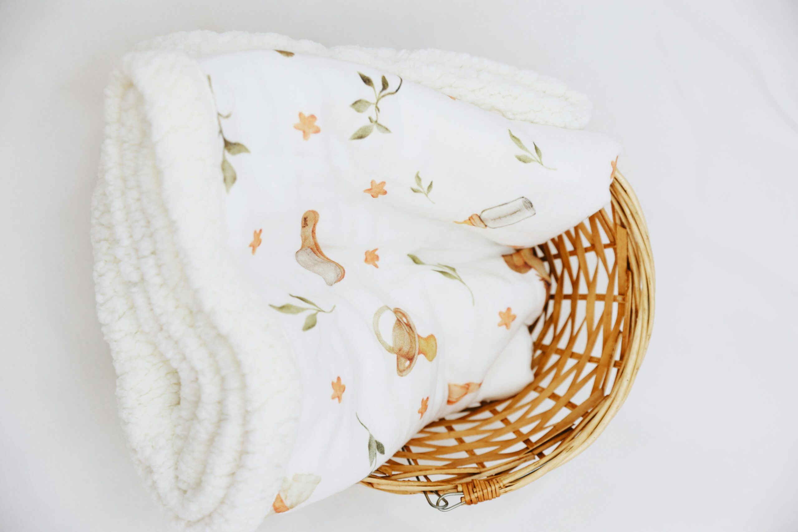 Soft baby blanket with pastel pattern in a wicker basket. Ideal for nursery decor.