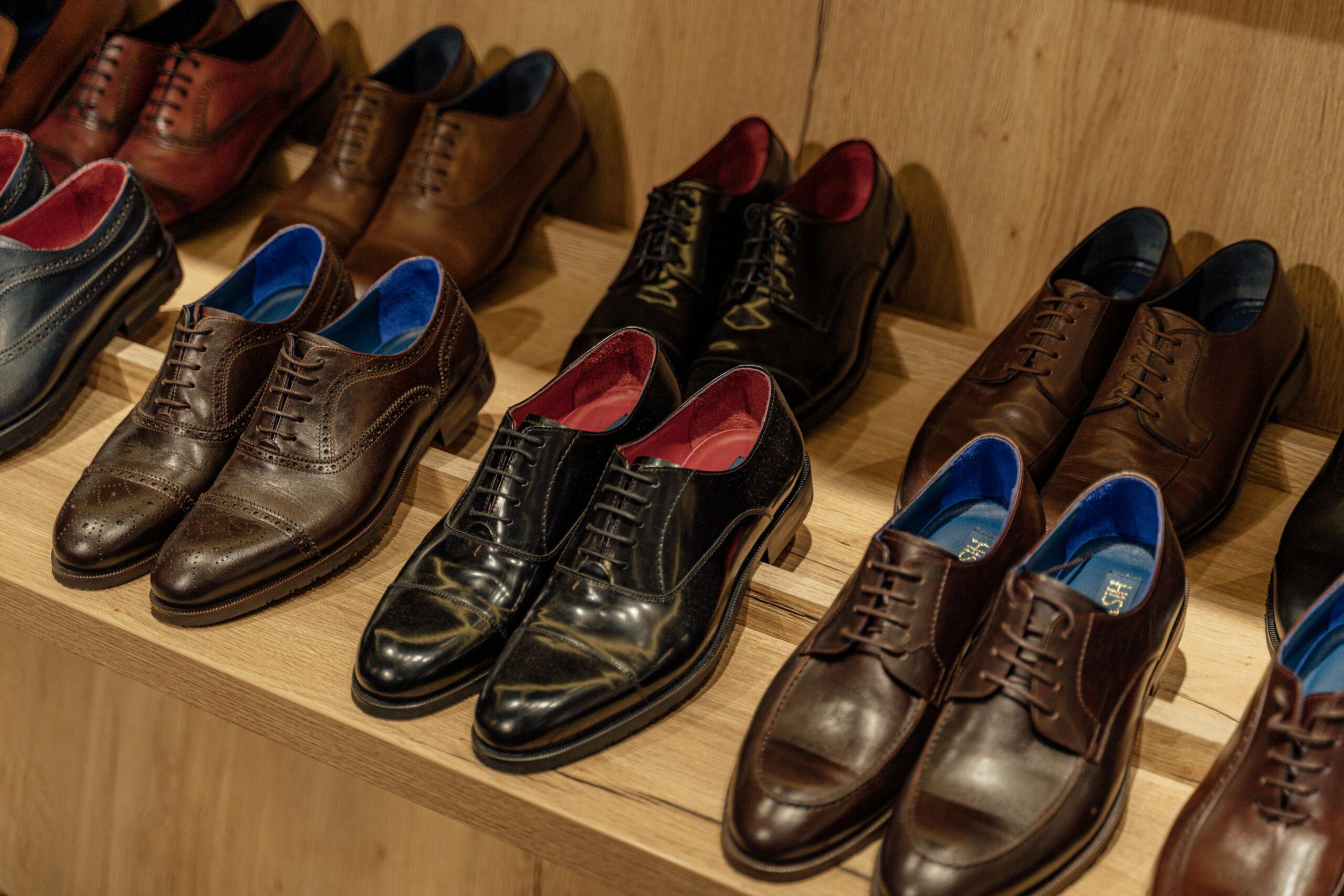 Showcase of elegant leather dress shoes on wooden shelves in-store display.